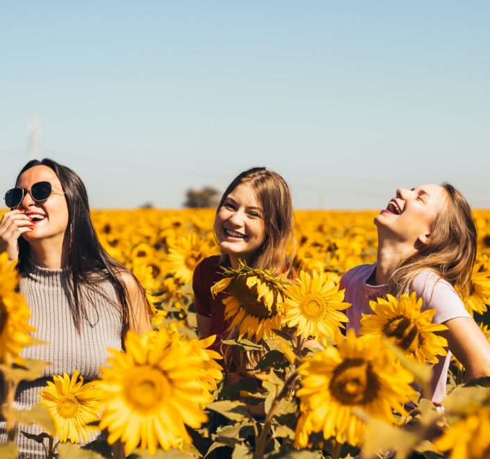 woman in white and black striped shirt standing on yellow sunflower field during daytime